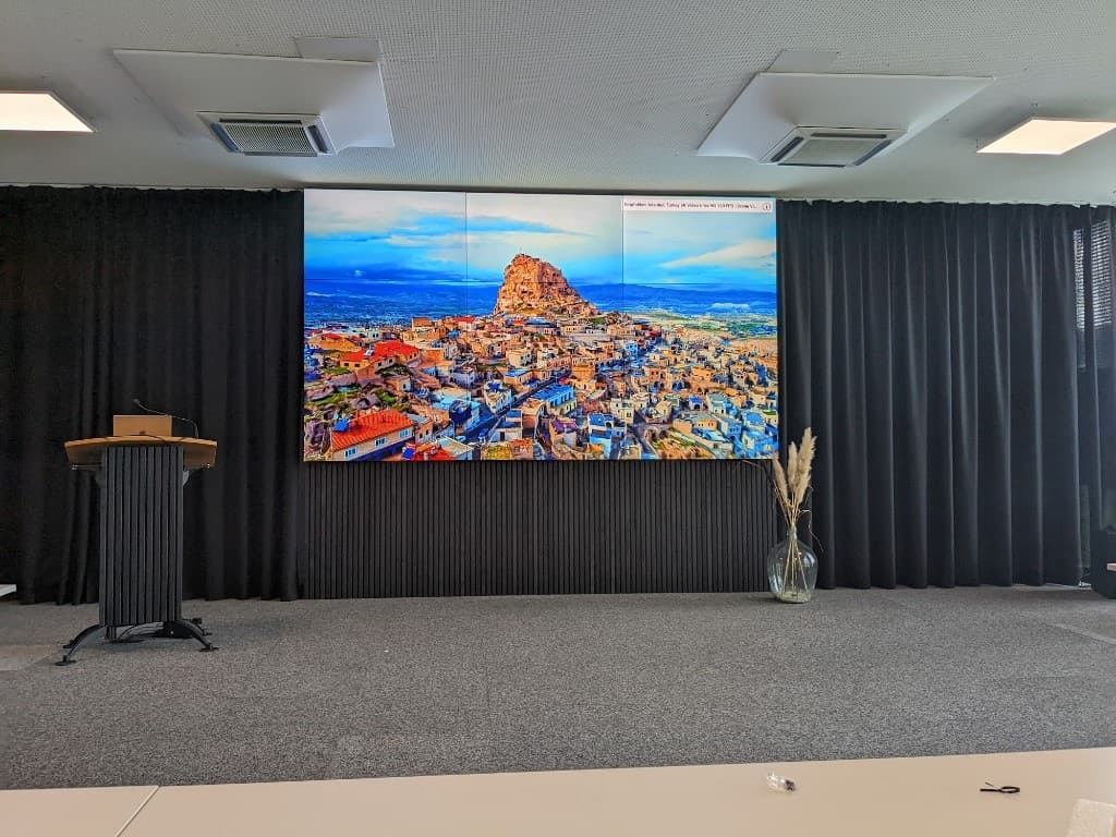 EventSpace im GlessHub: große Video-Wall, Rednerpult und dunkler Bühnen-Rücken für Präsentationen